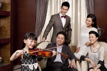 Little girl playing violin in front of family members