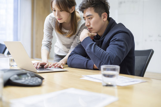 Business people using laptop in board room