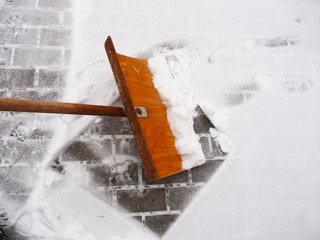 Winterdienst - Schnee schieben mit einem Schneeschieber aus Holz, Sicherheit auf Gehwegen...
