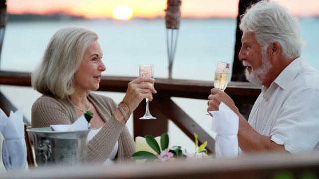 Caucasian senior couple enjoying evening beachfront dining 