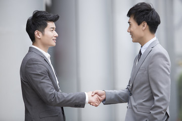 Young business person shaking hands outdoors