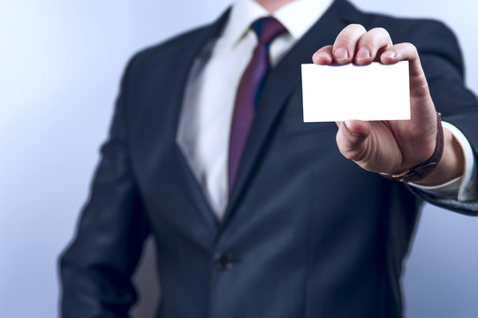 Man in dark suit holds business card 