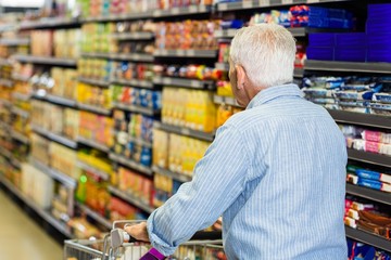 Rear view of senior man pushing trolley 