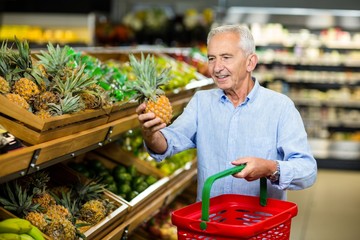 Smiling senior man picking pineapple 