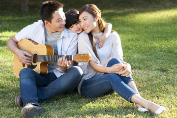 Young family in a park with a guitar