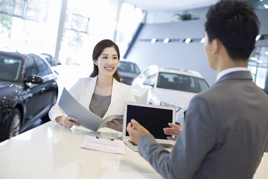 Young businesswoman buying car in showroom