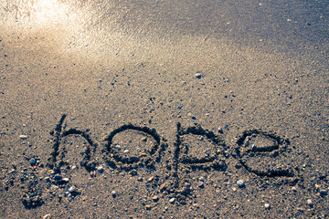 The inscription "HOPE" on a wet sand seacoast. Toned