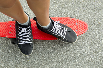 Black sneakers on a red skateboard