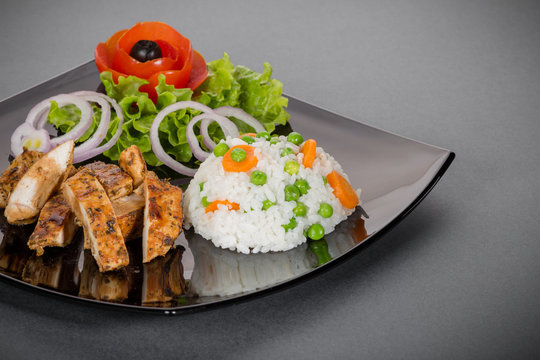 Grilled chicken meat with fresh vegetable salad over gray background