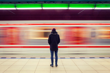 Long exposure of lonely man at subway station with blurry moving train - Powered by Adobe