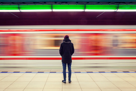 Long exposure of lonely man at subway station with blurry moving train