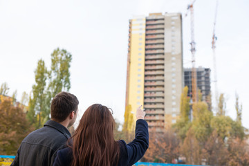 Young Couple Pointing Up at High Rise Building