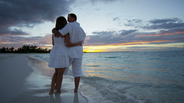 Young Caucasian couple on a luxury vacation beach at sunset