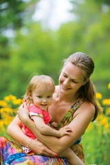 Young mother with her little baby on the meadow