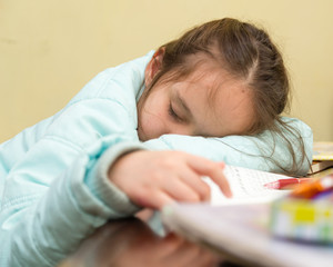 Young girl falling asleep doing homework