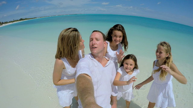 Selfie of Caucasian parents and daughters laughing on the beach 