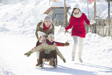 Happy family playing with sled in the snow