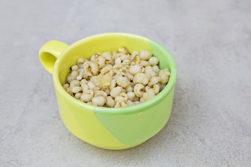 Job's tears boiled grains with syrup in Green cup for health on gray tile surface  (thai dessert from cereal) - copy space & Your text design
