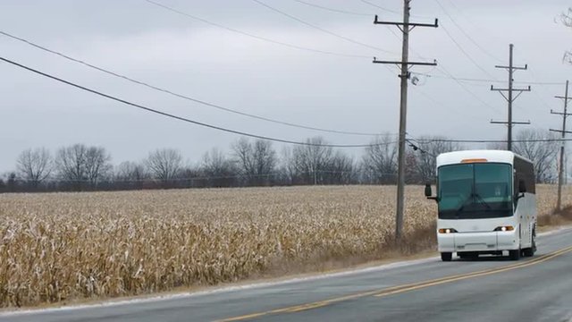 Coach (bus) passing a field of corn (maize).  Small camera pan, visuals colored for a cold, winter look.  Originally recorded in 4K, UHD.