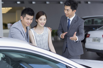 Young couple choosing car in showroom