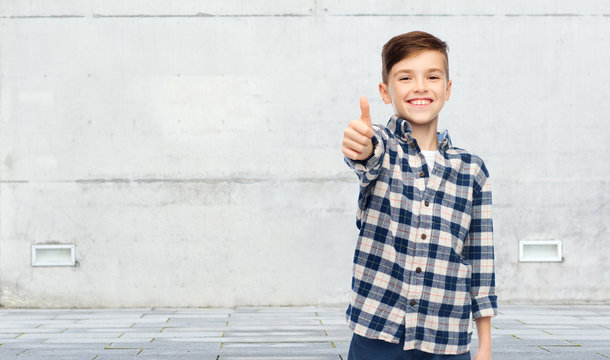 smiling boy in checkered shirt showing thumbs up