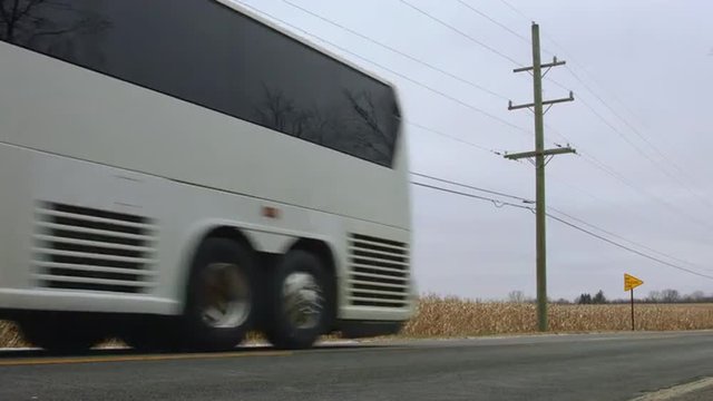Coach (bus) passing a field of corn (maize).  Low viewpoint, colored for a cold, winter look.  Originally recorded in 4K, UHD.
