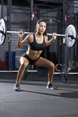 Fototapeta na wymiar Young woman lifting barbell at gym
