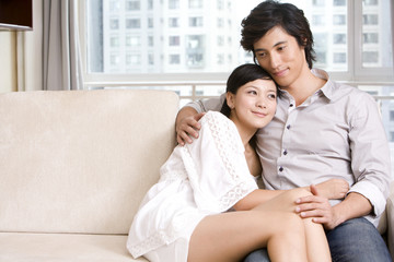 Asian couple cuddling on a sofa