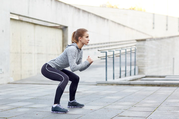 woman doing squats and exercising outdoors