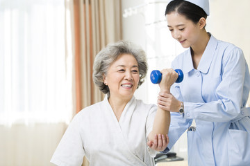 Nurse helping senior woman doing rehabilitation training