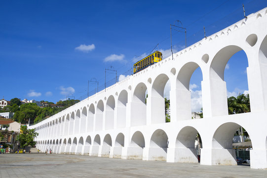 Bonde de Santa Teresa tram train drives along distinctive white arches of the landmark Arcos da Lapa in Centro of Rio de Janeiro Brazil