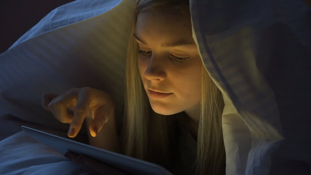 Young woman using a digital tab at night