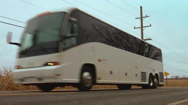 Coach (bus) passing a field of corn (maize).  Low viewpoint, colored for an autumn/fall look.  Originally recorded in 4K, UHD.