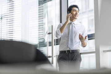 Young businessman talking on cell phone in office