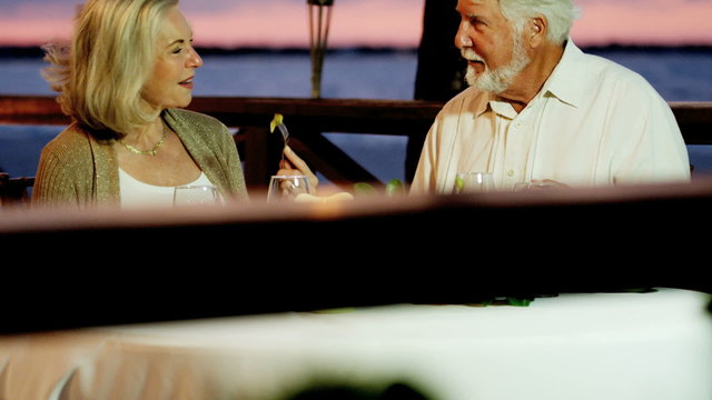 Happy Caucasian senior couple dining at beachfront hotel