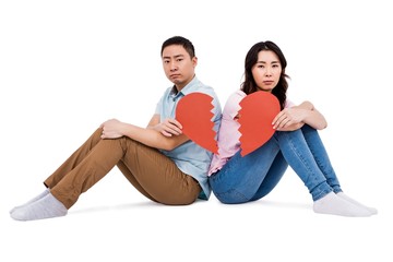 Portrait of sad couple holding broken heart pieces