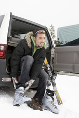 Man Sitting In Car, Putting On Ski Boots
