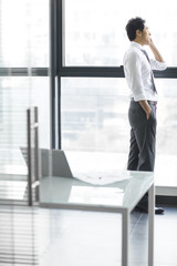 Young businessman talking on cell phone in office