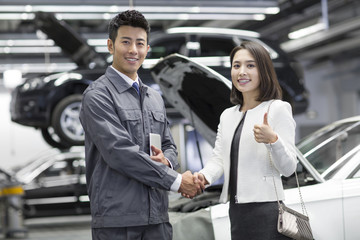 Auto mechanic and car owner shaking hands
