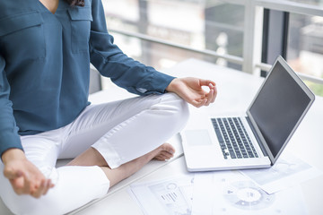 Young businesswoman doing yoga on office desk