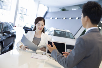 Young businesswoman buying car in showroom