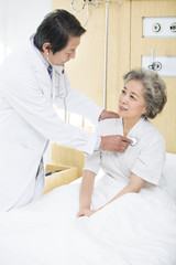 Doctor using stethoscope on patient in hospital