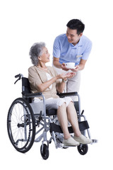 Plakat Male nursing assistant handing wheelchair bound woman a cup of coffee
