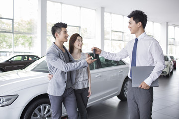 Young couple buying car in showroom