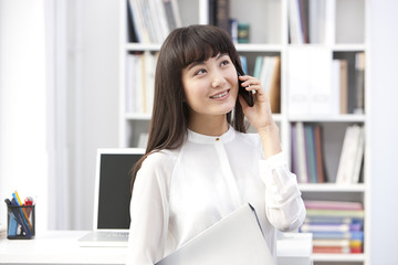 Cheerful young businesswoman on the phone in the office