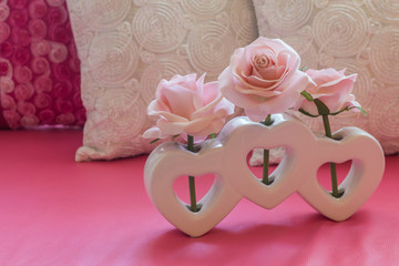 Artificial pink rose flower in heart shape vase