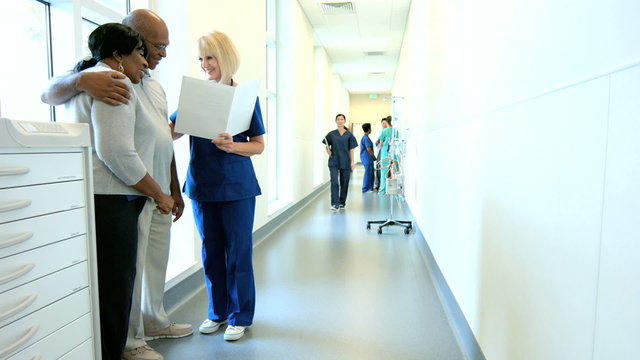 Caucasian female staff consulting with African American couple in medical center