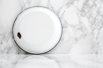 Backside of White Vintage Enamel Plate on White Marble Background