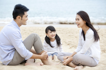 Cheerful young family sitting and chatting on the beach of Repulse Bay, Hong Kong 