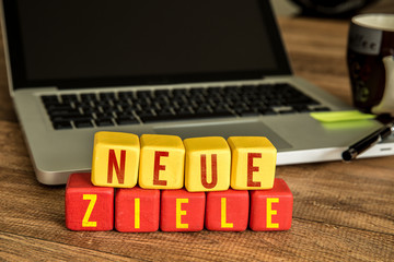 New Goals (in German) written on a wooden cube in a office desk